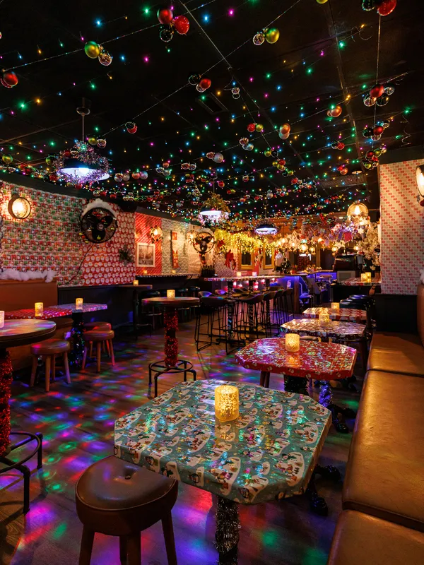 At Project Gigglewater in Toronto, a Christmas bar 
            delights guests with festively decorated tables draped in colorful 
            tablecloths, surrounded by hanging ornaments and twinkling string lights. 
            Glowing candles complete the vibrant and cozy atmosphere, making it the 
            perfect holiday haven.